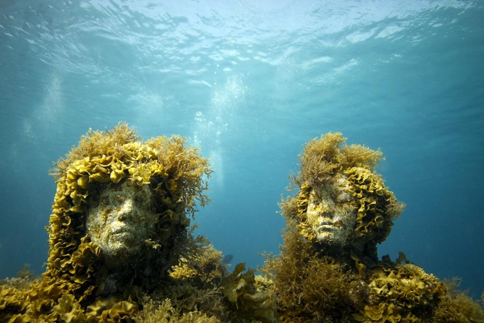 Jason deCaires Taylor's underwater statue covered with sea weed.
